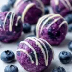No-bake blueberry cheesecake protein bites on a platter with berries