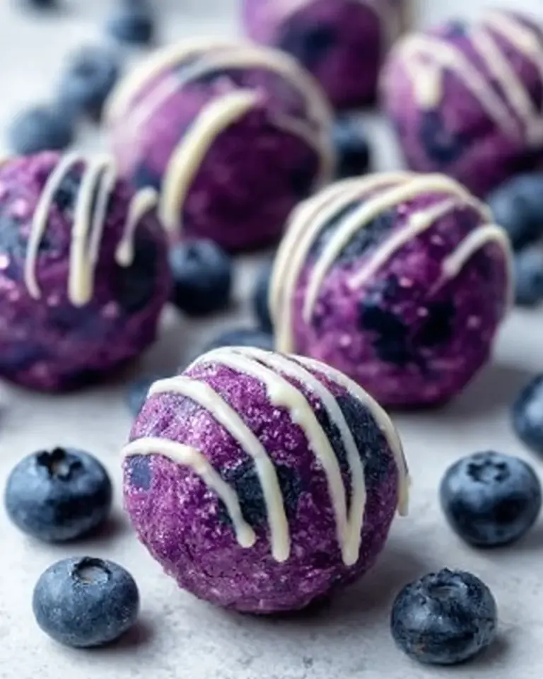 No-bake blueberry cheesecake protein bites on a platter with berries
